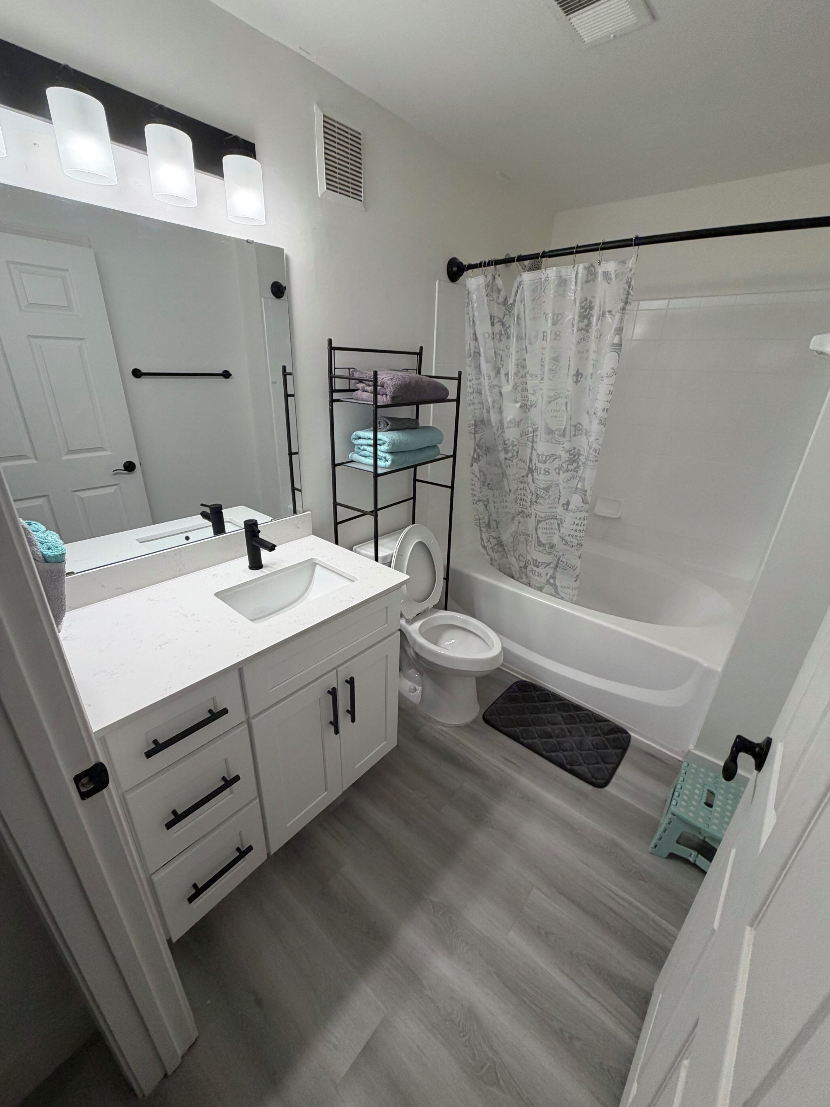 Een badkamer met een witte wastafel, spiegel, toilet en bad.