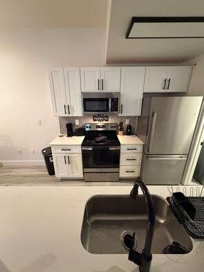 A kitchen with white cabinets, a microwave, a stove, and a refrigerator. - Delightful 2-bedroom apartment with AC in Summerville (Summerville)