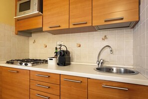 A kitchen with wooden cabinets, a stainless steel sink, a microwave, and a gas stove. - Just a short walk from the Ponte Vecchio, far from the noise (Firenze)