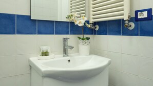 Un baño con lavamanos blanco, espejo y pared con azulejos azules.