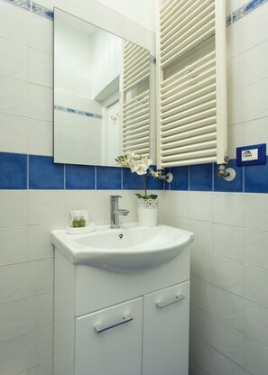 A bathroom with a white sink, mirror, and blue-tiled wall. - Just a short walk from the Ponte Vecchio, away from the noise (Firenze)