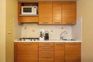 A kitchen with wooden cabinets, a microwave, a gas stove, a coffee maker, and a sink. - Just a short walk from the Ponte Vecchio, away from the noise (Firenze)