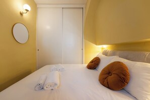 A hotel room with a bed, a white door, a round mirror, and a wall-mounted light fixture. - Just a short walk from the Ponte Vecchio, away from the noise (Firenze)