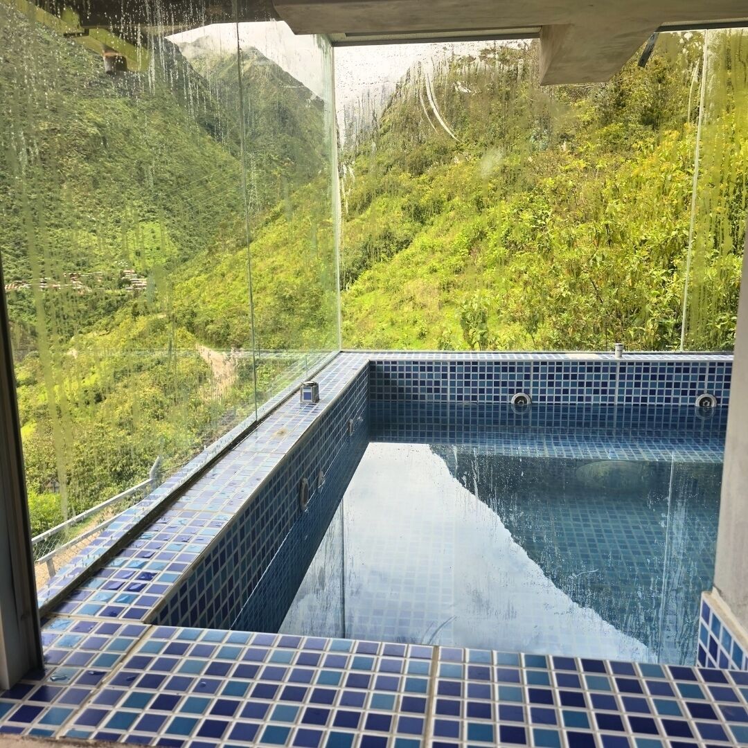 A hot tub with a view of a lush green hillside.