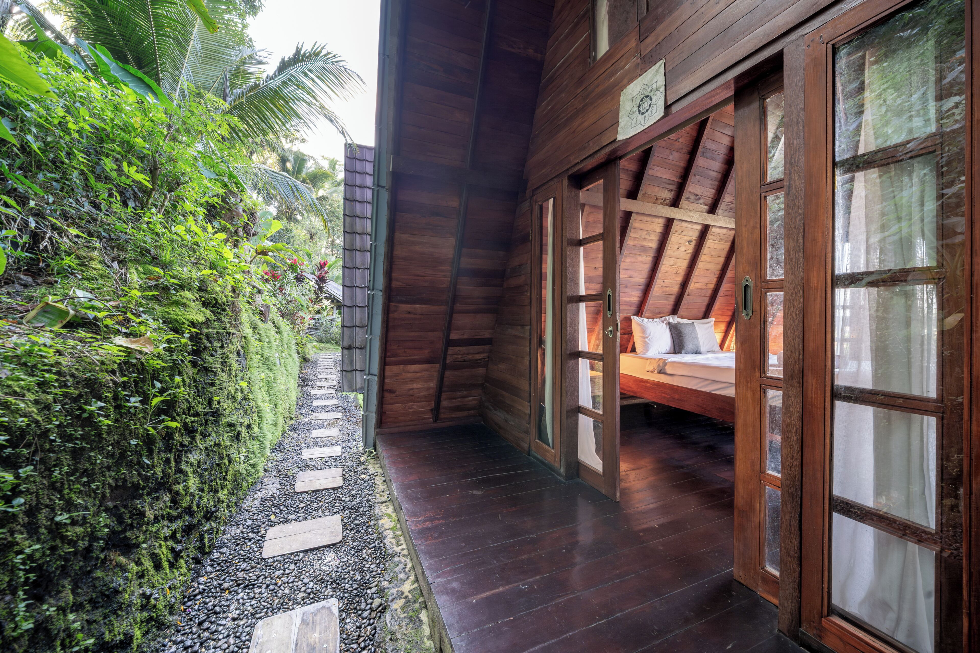 A wooden building with a sloped roof, a bed with pillows, and a small window.