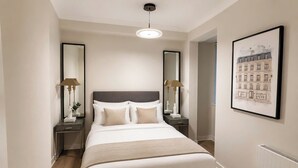 Ein modernes Hotelzimmer mit einem großen Bett, zwei Nachttischen mit Lampen, einem Stadtbild als Bild und einem Heizkörper.