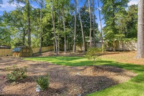 A backyard with a wooden shed, a small tree, and a grassy lawn. - Modern Gem in the Heart of Alpharetta, minutes to Avalon and HWY 400 (Alpharetta)