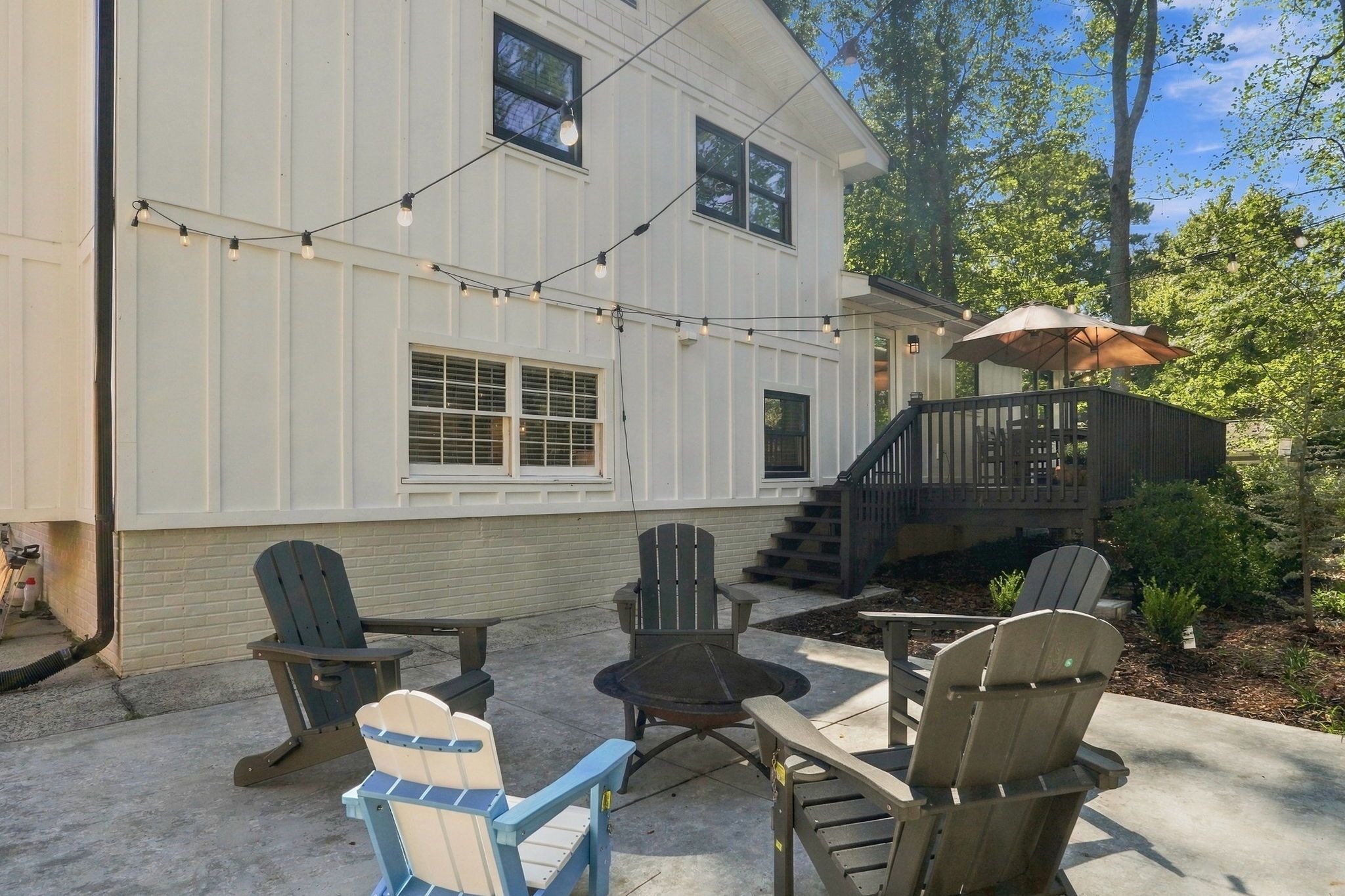 A house with a covered outdoor seating area, a staircase leading to a deck, and string lights.