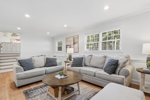 A modern living room with a grey sofa set, a coffee table, and a bookshelf. - Modern Gem in the Heart of Alpharetta, minutes to Avalon and HWY 400 (Alpharetta)