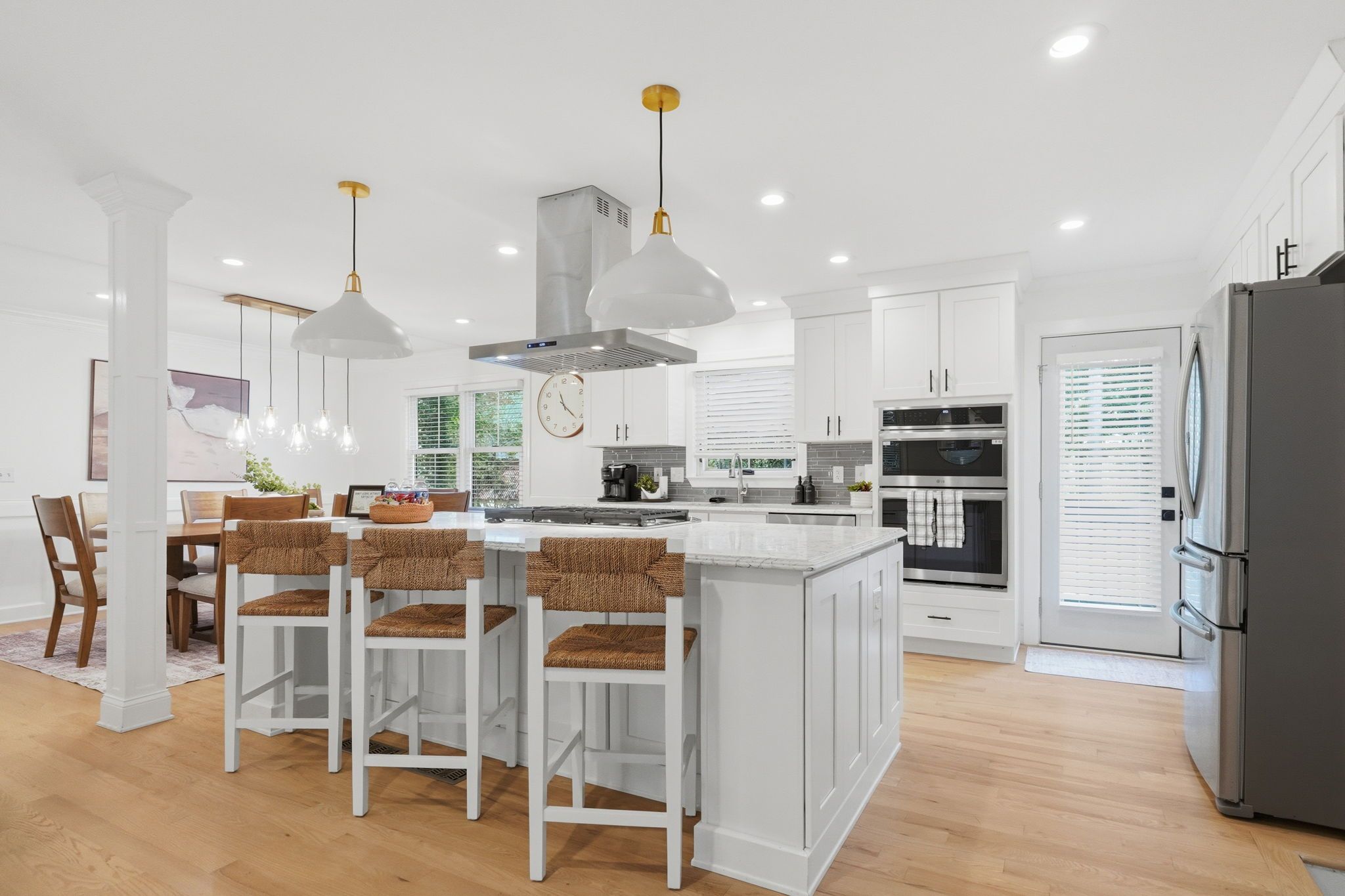 A modern kitchen with white cabinetry, stainless steel appliances, and a central island with bar stools.