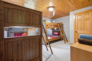 A bunk bed room with wooden walls and ceiling, a ladder, and a door. - Peak and Pine Hideway / Hot Tub & Arcade (Bethel)