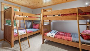 A room with two bunk beds, a wooden ladder, and a window with a view of greenery. - Peak and Pine Hideway / Hot Tub & Arcade (Bethel)