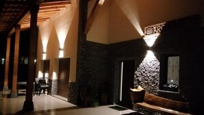 A hotel lobby with a stone wall, a wooden bench, and a sign that reads 'ARC'.