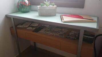 Een bureau met een potplant, een notitieboekje en informatiefolders.