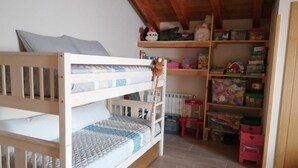 A bunk bed with a ladder, a storage shelf with toys, and a radiator.