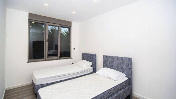 Un dormitorio con dos camas, una ventana y una puerta.