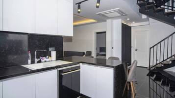 A modern kitchen with white cabinets, a black countertop, and a built-in dishwasher.