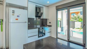 Una cocina moderna con electrodomésticos integrados y un ventanal que da a una zona de piscina.