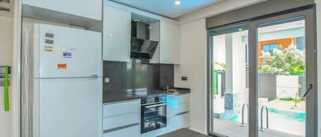 Una cocina moderna con electrodomésticos integrados y un ventanal que da a una zona de piscina.