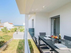 A balcony with a dining table, chairs, and a bottle of wine. - Apartment Alisa, Liznjan: A modern apartment with a sea view (Marčana)