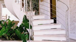 A spiral staircase with metal railings and white steps, leading to a room with a textured wall and a door. - Casa Playa, Las Iguanas CapCana (Punta Cana)