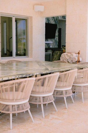 A dining area with a marble table and wicker chairs. - Casa Playa, Las Iguanas CapCana (Punta Cana)