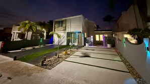 Ett modernt hus med en uppfart, en liten trädgård och en pool.