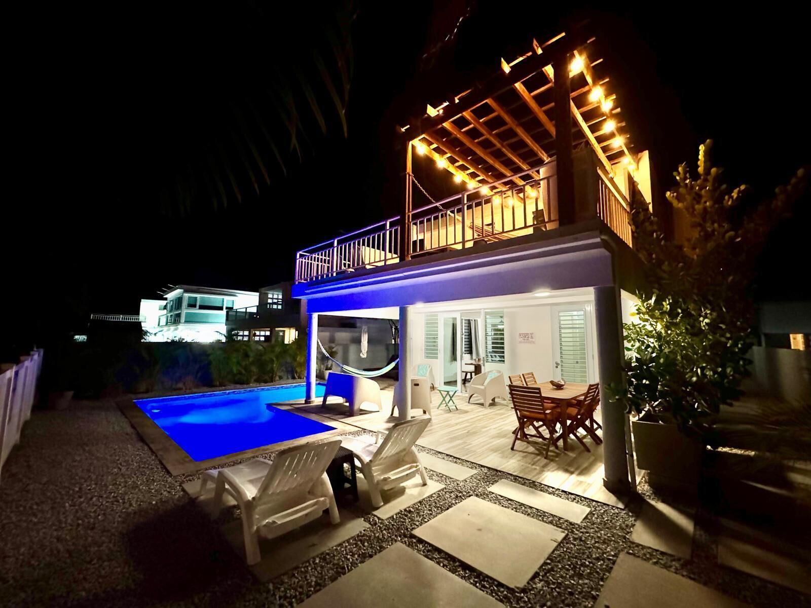 A two-story house with a swimming pool, outdoor seating, and a covered patio area.