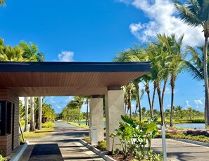 A covered walkway with palm trees and a clear sky.