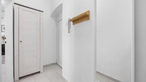 Ein Flur mit einer geschlossenen Tür, einem Holzregal und einem Lichtschalter an der Wand.