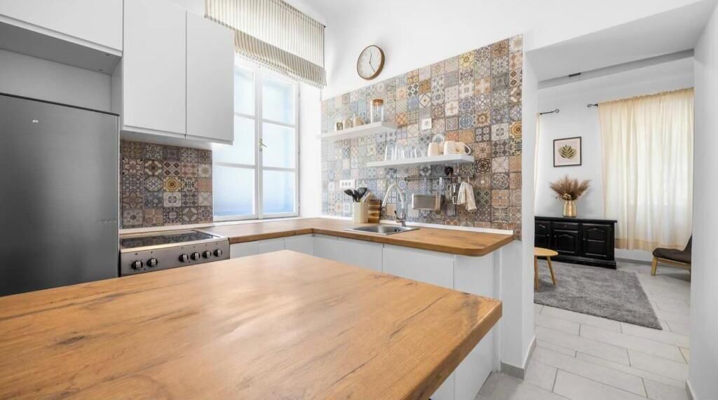 A modern kitchen with a wooden countertop, stainless steel appliances, and a tiled backsplash.