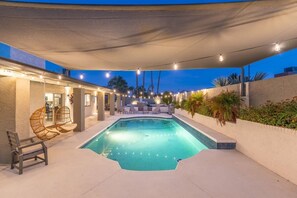 A swimming pool with a covered patio area, outdoor seating, and string lights. - Epic PHX Fun-Game Room•Pool•Hot Tub•Mtn Views (Phoenix)