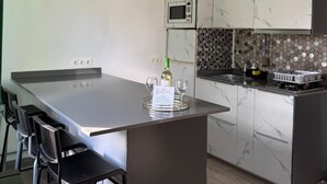 Eine moderne Küche mit Kochinsel, Barhocker, einer Mikrowelle und einer Weinflasche.