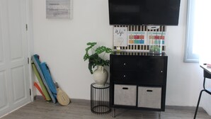 Ein Zimmer mit Fernseher, Pflanze, Schrank und einem Poster an der Wand.