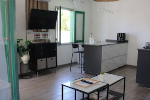 A modern kitchen with a TV, bar stools, a coffee machine, and a small dining table. - RockBeach Bungalow in Costa Teguise - A Quiet Oasis with a Private Terrace and Pool (Costa Teguise)
