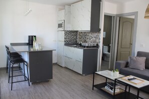 A compact kitchen with a central island, bar stools, a microwave, and a coffee machine. - RockBeach Bungalow in Costa Teguise - A Quiet Oasis with a Private Terrace and Pool (Costa Teguise)