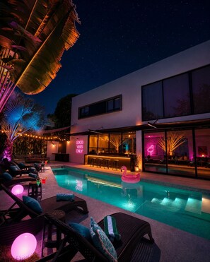 Ein moderner Poolbereich mit Liegestühlen, einer Bar und einem Pool.