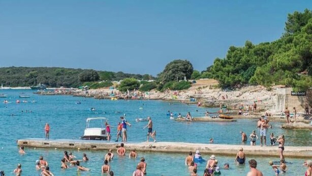 Eine Küstenlandschaft mit einem Schwimmbereich, Booten und einer felsigen Uferlinie.