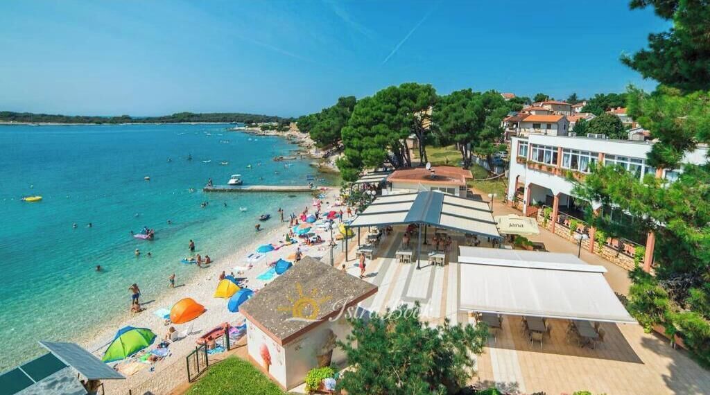 Un hôtel situé en bord de mer, doté d’une piscine, de parasols et offrant une vue sur l’océan.
