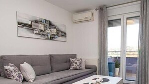 Un soggiorno con un divano grigio, un tavolino da caffè e un quadro appeso al muro.