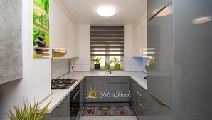 Una cucina compatta con piano cottura integrato, una finestra con persiane e un piccolo lavello.