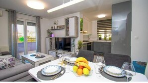 Un soggiorno moderno con zona pranzo, cucina e balcone con tende.
