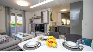 Ein modernes Wohnzimmer mit Essbereich, einer Küche und einem Balkon mit Vorhängen.