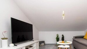 A modern living room with a flat-screen TV, a sofa with cushions, a small round table, and a ceiling light fixture. - Megy Apartment with Ocean View, Medulin (Marčana)