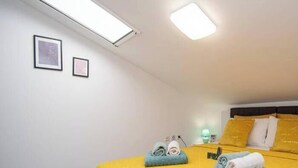 A bedroom with a bed, pillows, a bedside table, a lamp, and a wall-mounted light fixture. - Megy Apartment with Ocean View, Medulin (Marčana)