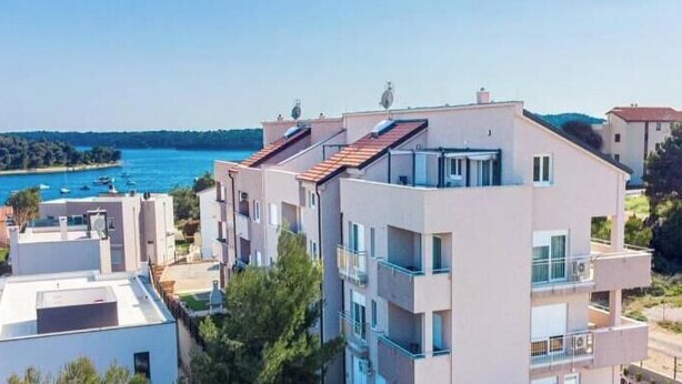 A multi-story building with balconies, a swimming pool, and a view of the sea. - Megy Apartment with Ocean View, Medulin (Marčana)