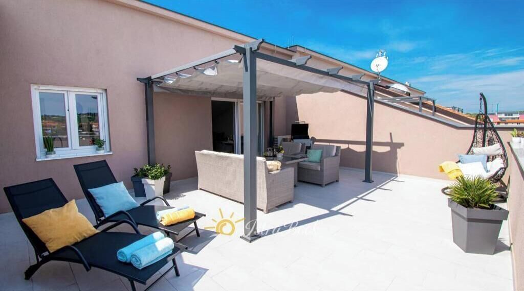 Une terrasse sur le toit avec des sièges extérieurs, une pergola et des plantes en pot.