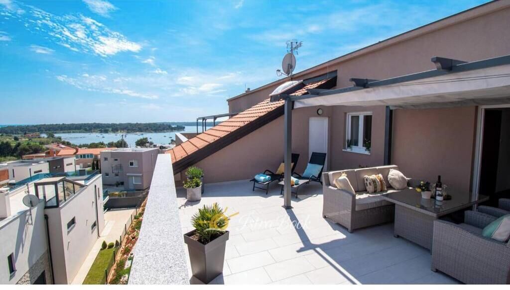 Une terrasse sur le toit, aménagée avec du mobilier d’extérieur, une antenne parabolique et offrant une vue sur la mer.