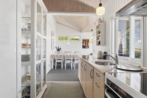 A modern kitchen with a dining area, wooden cabinets, and a large window.