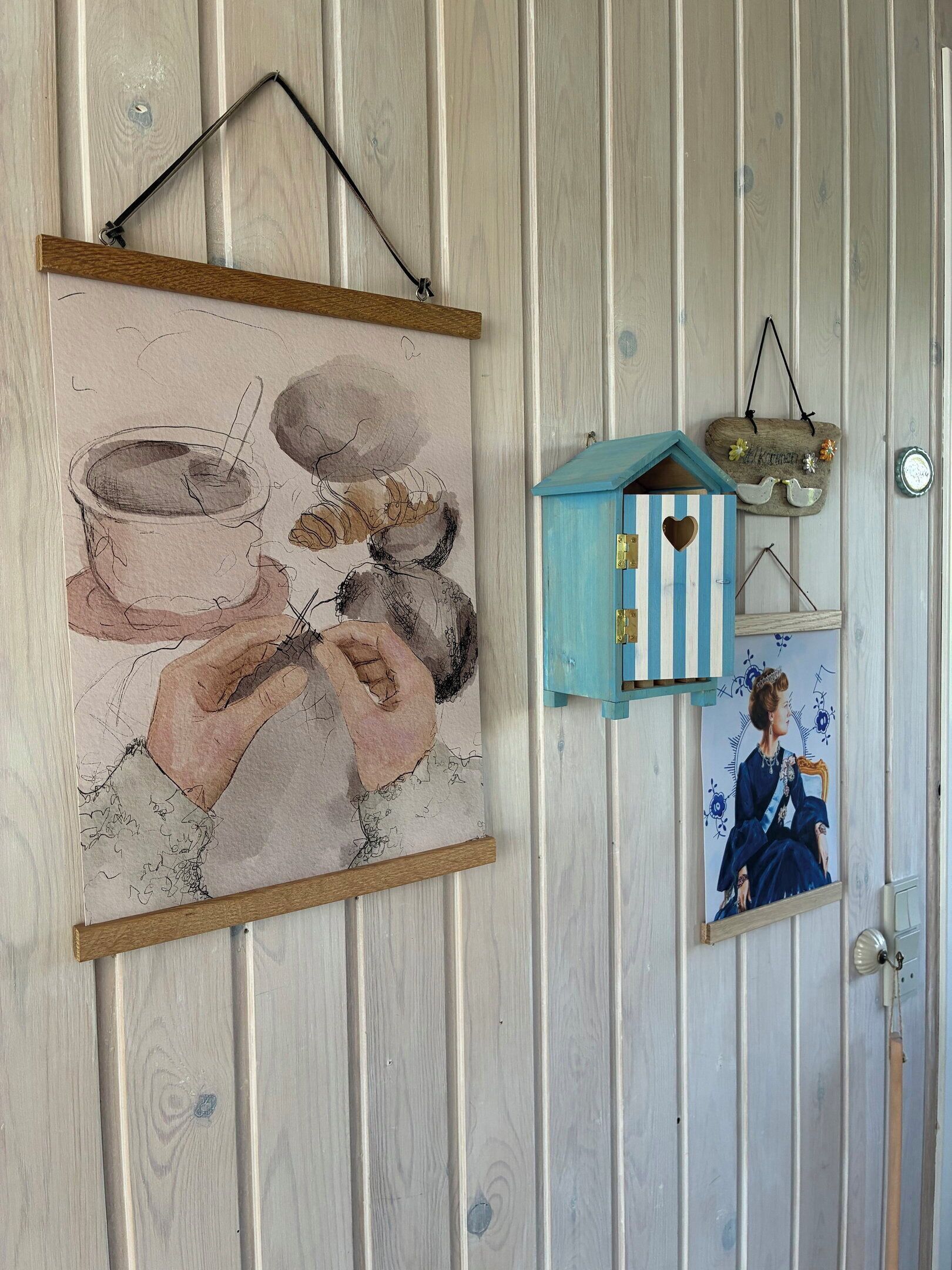 A wall with a framed painting, a small birdhouse, and a framed picture.